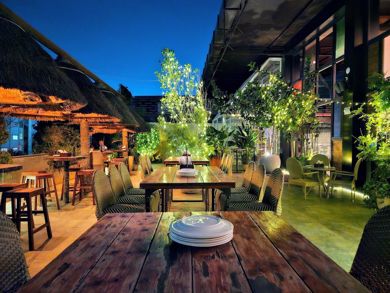 Rooftop terrace at dusk — thatched cabanas and fairy lights